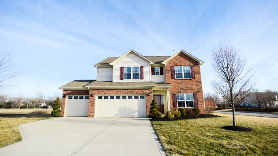 Two-story brick and wood home with driveway and landscaping